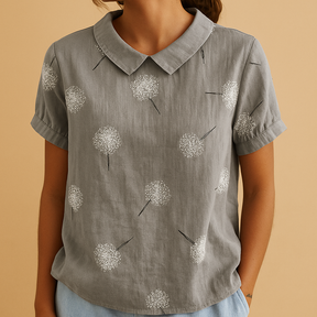 Vrouw draagt een luchtige blouse met vrolijke bloemenprint, ideaal voor zomerse dagen en casual outfits